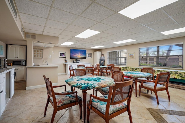 tiled dining area featuring a drop ceiling