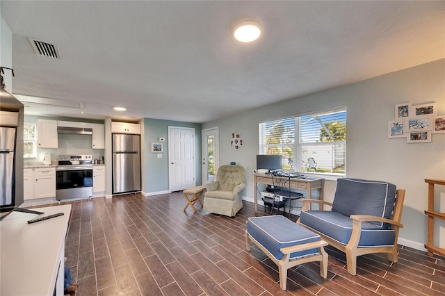 living area featuring wood tiled floor, visible vents, and baseboards