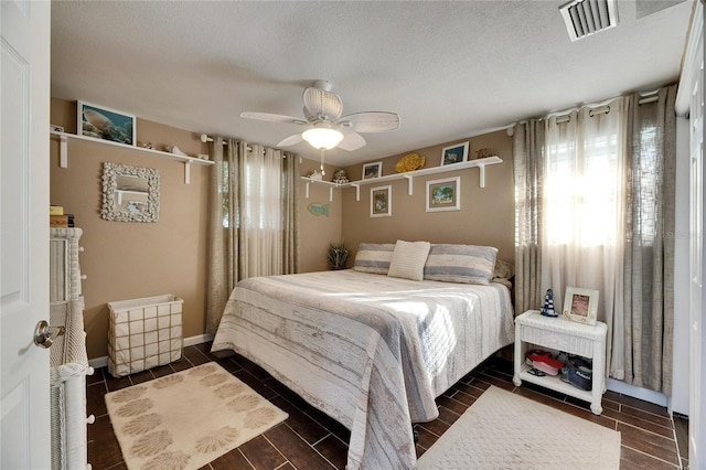 bedroom with wood finish floors, visible vents, a ceiling fan, a textured ceiling, and baseboards