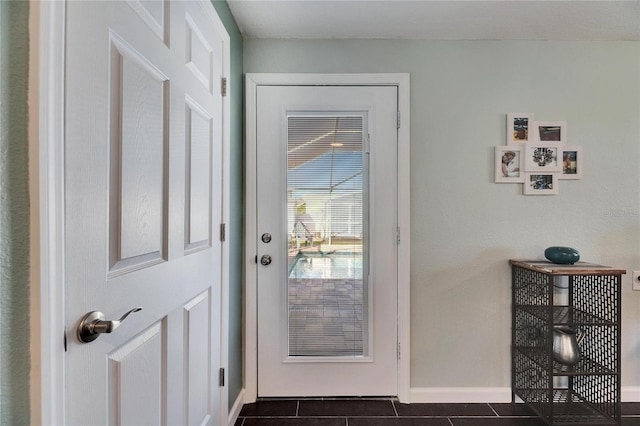 doorway to outside featuring dark tile patterned floors and baseboards