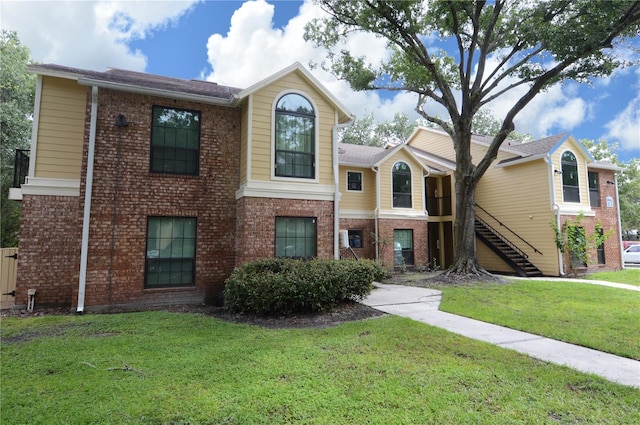 view of front of home featuring stairs, a front yard, and brick siding