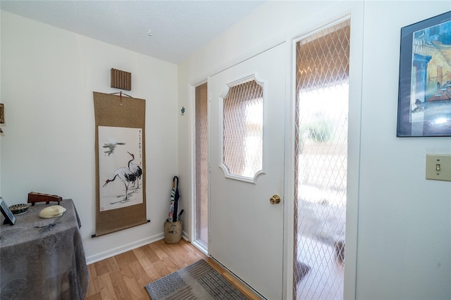 entryway featuring light wood-style floors, baseboards, and a textured ceiling