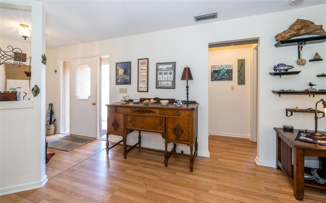 foyer entrance with light wood-style floors, visible vents, and baseboards