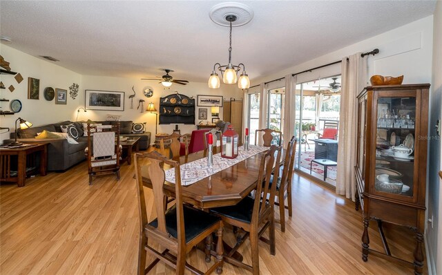 dining space with light wood-type flooring, a textured ceiling, visible vents, and ceiling fan