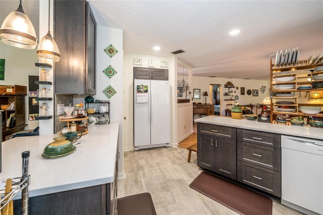 kitchen featuring pendant lighting, white appliances, light wood-style floors, a peninsula, and light countertops