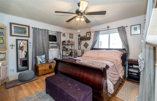 bedroom featuring cooling unit, a ceiling fan, light wood finished floors, and a textured ceiling