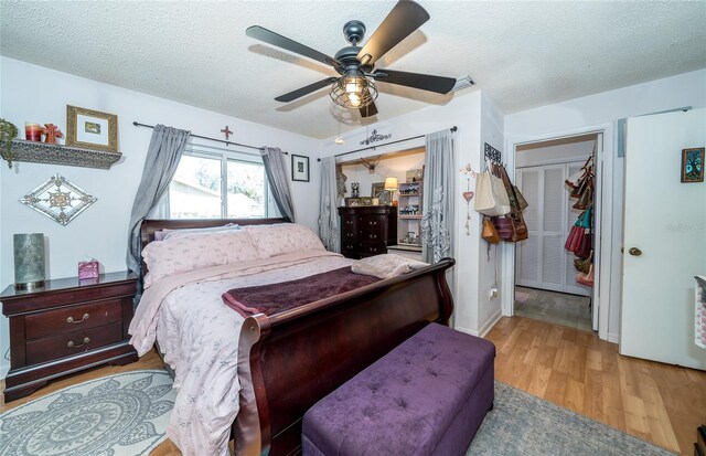 bedroom with a ceiling fan, wood finished floors, and a textured ceiling