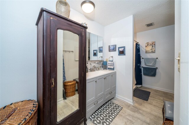 bathroom with visible vents, a textured ceiling, wood finished floors, a shower with shower curtain, and vanity