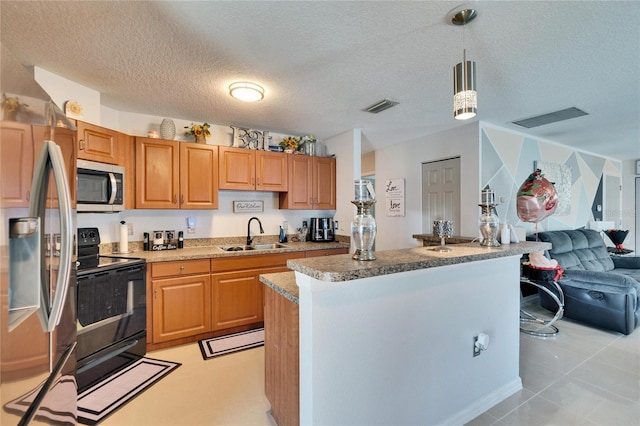 kitchen with stainless steel appliances, a kitchen island, visible vents, a sink, and decorative light fixtures