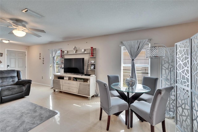 dining room featuring a textured ceiling, light tile patterned floors, visible vents, a ceiling fan, and baseboards