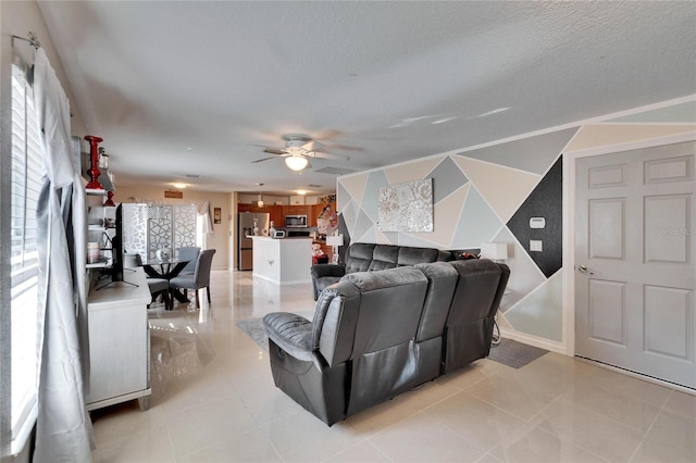 living area with light tile patterned floors, ceiling fan, and a textured ceiling