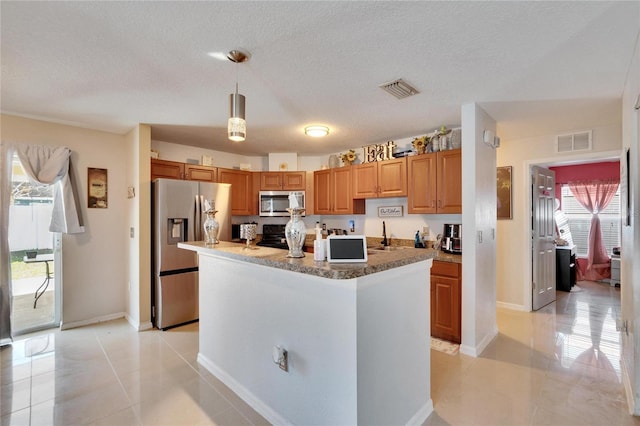 kitchen featuring appliances with stainless steel finishes, brown cabinetry, decorative light fixtures, and visible vents