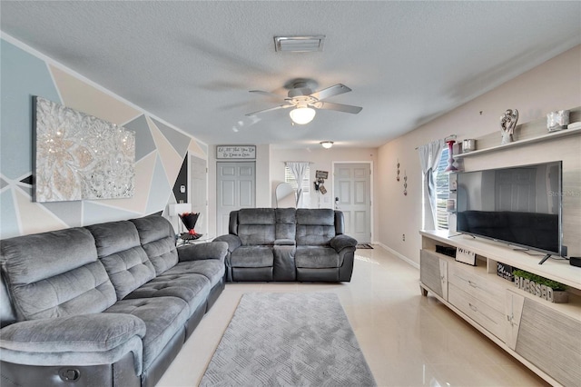 living area featuring a textured ceiling, ceiling fan, visible vents, and baseboards