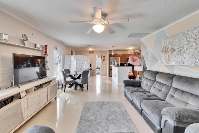 living area with ceiling fan, a textured ceiling, and light tile patterned floors