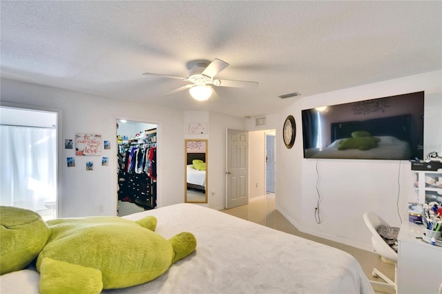 bedroom with connected bathroom, a spacious closet, visible vents, and a textured ceiling