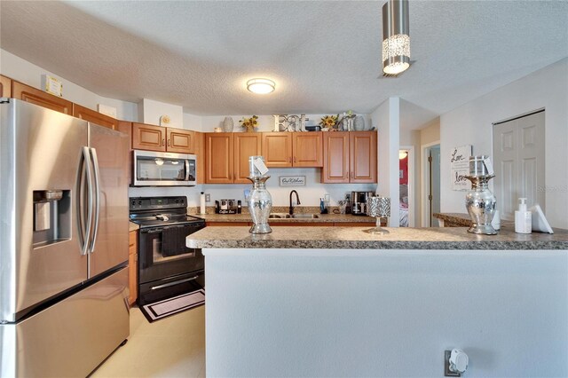 kitchen with pendant lighting, stainless steel appliances, light countertops, a sink, and a textured ceiling