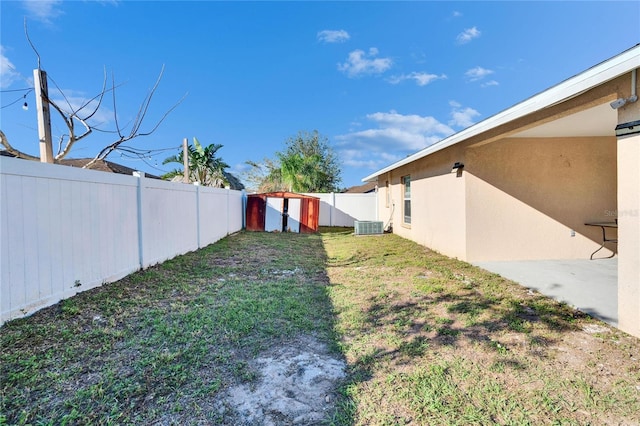 view of yard featuring cooling unit, a fenced backyard, an outdoor structure, and a storage unit