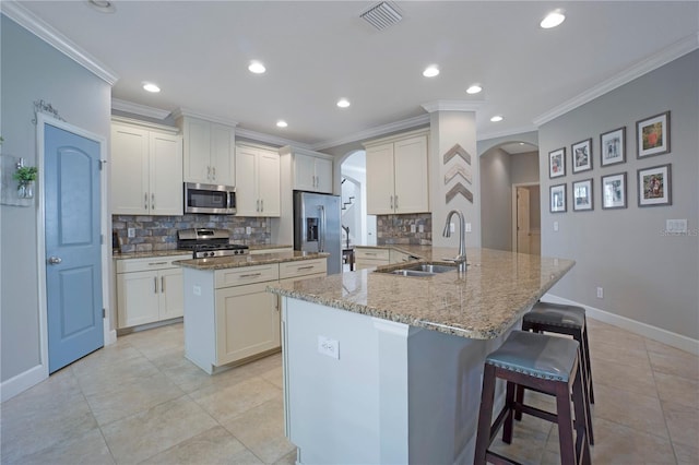 kitchen featuring arched walkways, light stone counters, a breakfast bar, visible vents, and appliances with stainless steel finishes