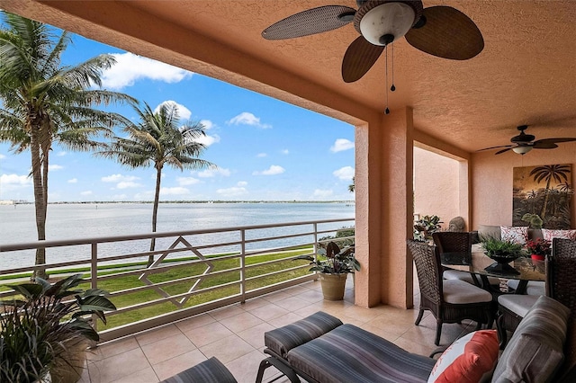 balcony with a water view, a sunroom, and ceiling fan