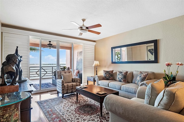 living room featuring a water view, plenty of natural light, a textured ceiling, and wood finished floors