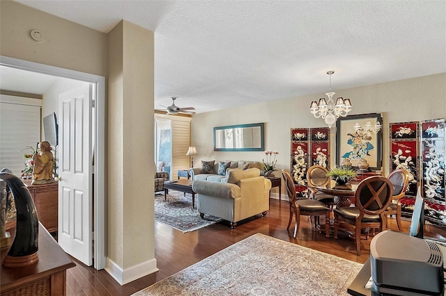 living room with baseboards, dark wood finished floors, a textured ceiling, and ceiling fan with notable chandelier