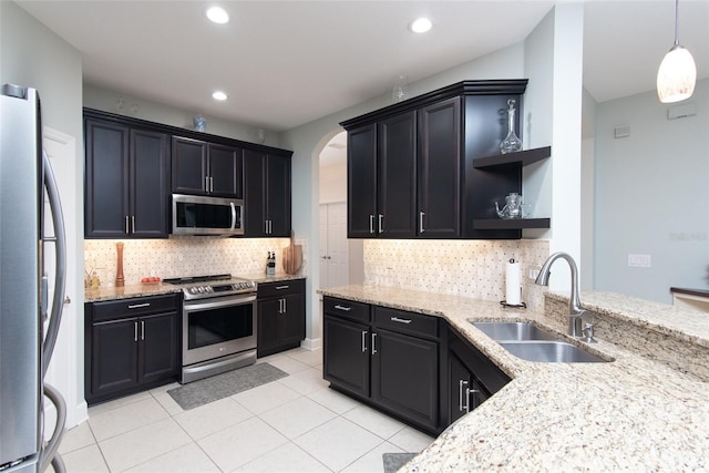 kitchen with sink, light tile patterned floors, appliances with stainless steel finishes, backsplash, and hanging light fixtures