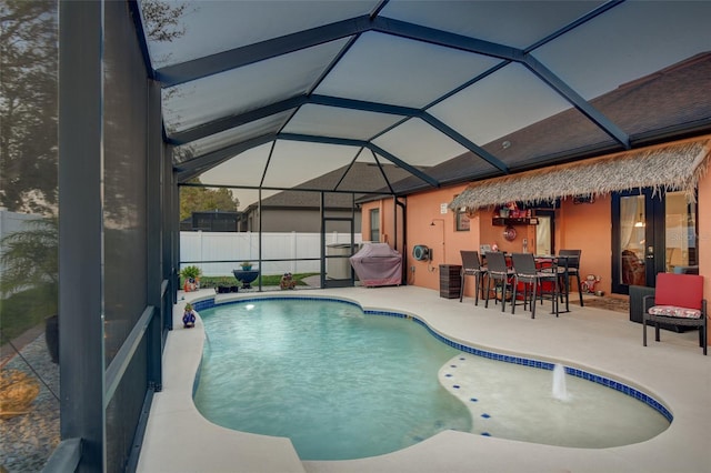 view of swimming pool with exterior bar, a patio area, pool water feature, and glass enclosure