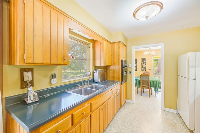 kitchen featuring white refrigerator, a notable chandelier, sink, and oven