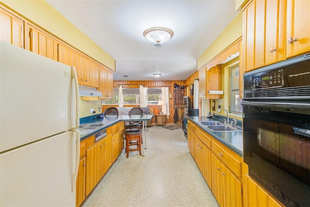 kitchen featuring white refrigerator, sink, a kitchen breakfast bar, and black oven