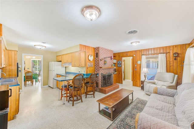 living room with sink, wooden walls, and a brick fireplace