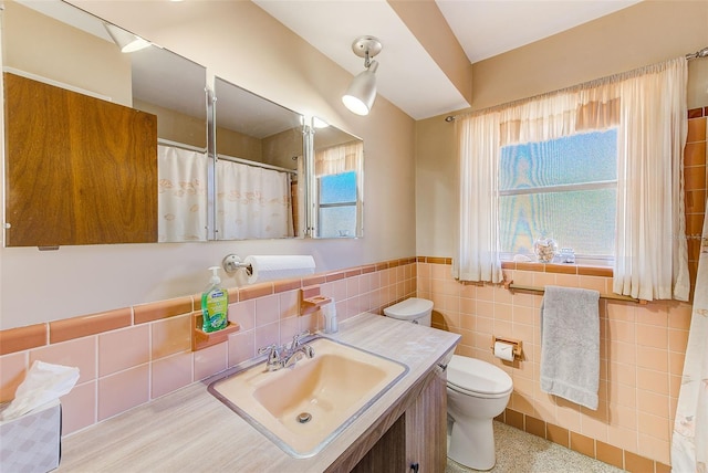 bathroom with vanity, tile walls, and toilet