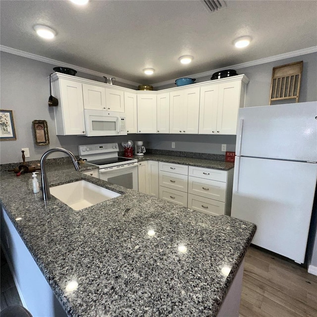 kitchen featuring white cabinetry, sink, white appliances, and kitchen peninsula
