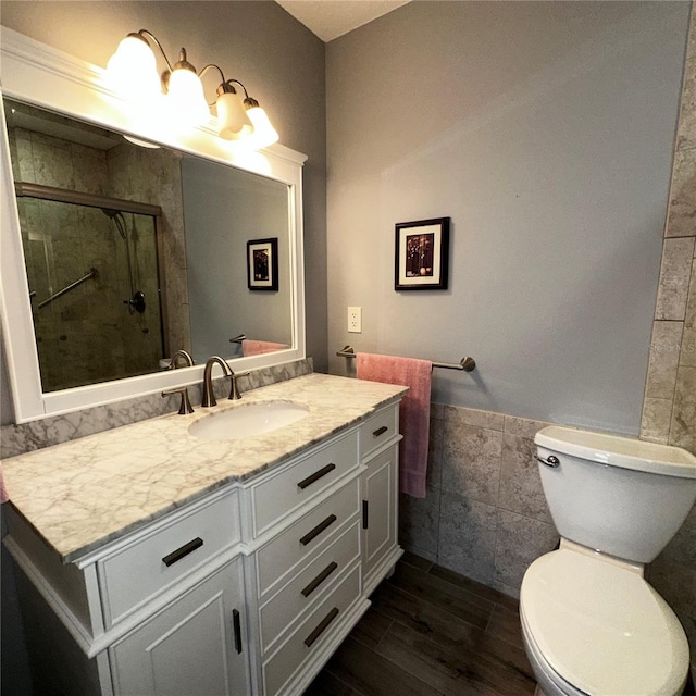 bathroom with wood-type flooring, tile walls, vanity, walk in shower, and toilet