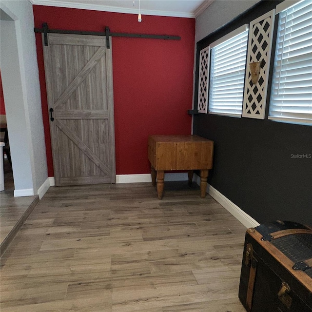 interior space with wood-type flooring, ornamental molding, and a barn door