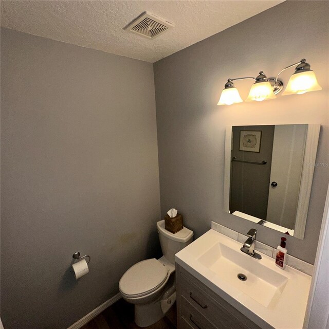 bathroom with vanity, a textured ceiling, and toilet
