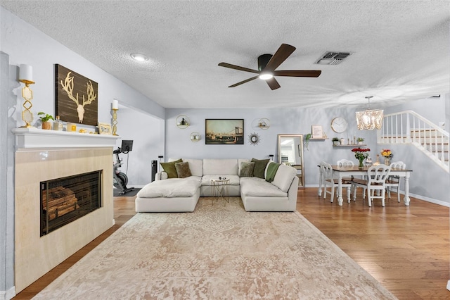 living area with visible vents, stairway, wood finished floors, a textured ceiling, and a fireplace