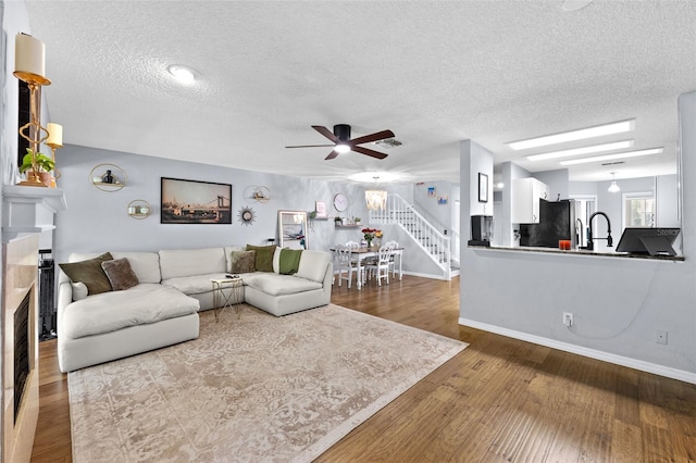 living area with a fireplace, visible vents, stairway, a textured ceiling, and wood finished floors