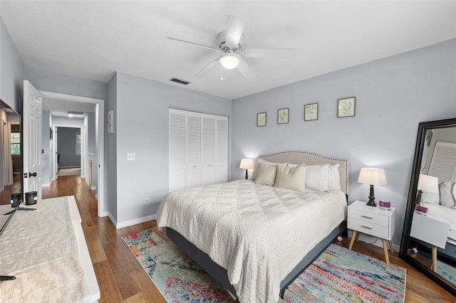 bedroom with visible vents, baseboards, a ceiling fan, wood finished floors, and a closet