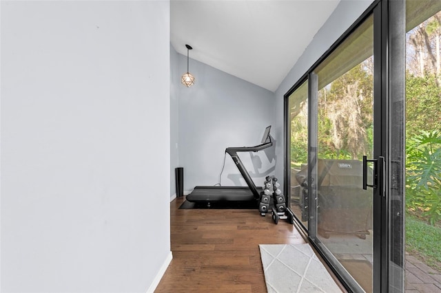 workout room featuring baseboards, vaulted ceiling, and wood finished floors