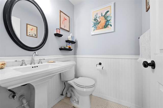 bathroom with a wainscoted wall, a sink, and toilet