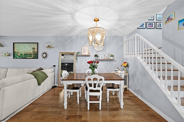 dining area featuring a textured ceiling, stairs, a chandelier, and wood finished floors