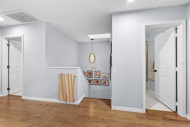 interior space featuring wood finished floors, an upstairs landing, visible vents, and baseboards