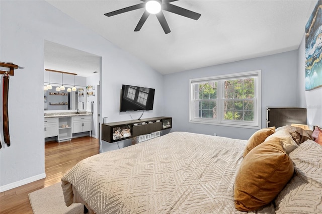 bedroom with baseboards, lofted ceiling, ceiling fan, wood finished floors, and a sink