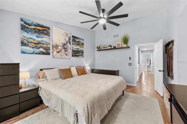 bedroom with baseboards, visible vents, ceiling fan, and light wood finished floors