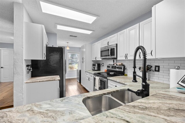 kitchen featuring stainless steel appliances, dark wood finished floors, white cabinetry, and light stone countertops