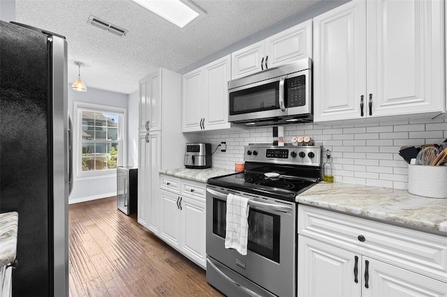 kitchen featuring appliances with stainless steel finishes, visible vents, white cabinetry, and dark wood-style floors