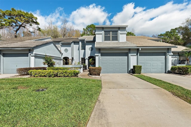 view of front of home featuring a garage, a tile roof, driveway, stucco siding, and a front lawn