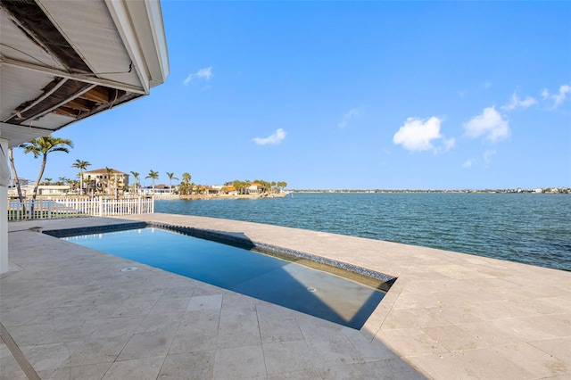 pool with a patio, a water view, and fence