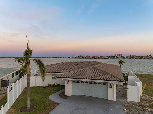 view of front of property with concrete driveway, a water view, fence private yard, and a tile roof