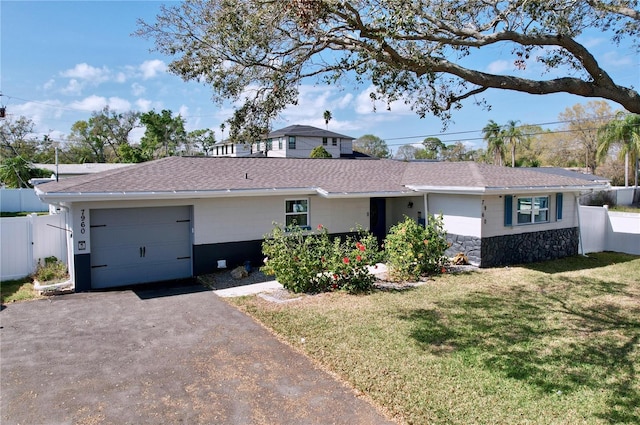 ranch-style house featuring an attached garage, a front yard, fence, stone siding, and driveway